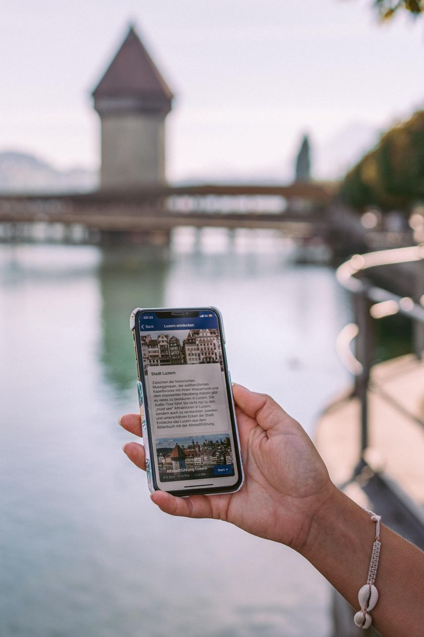 Person mit Smartphone und Kopfhörern nutzt den Audio-Guide bei einem Stadtrundgang durch Luzern.